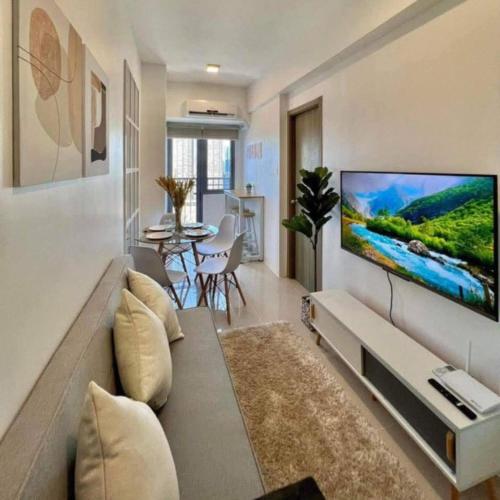 a living room with a large flat screen tv on a wall at Stylish City Escape in Mandaluyong - Central Condo Living in Manila
