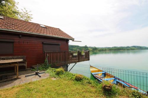 a house and a boat on the side of a lake at Rare petit chalet sur le lac barque à rames clim in Aiguebelette-le-Lac