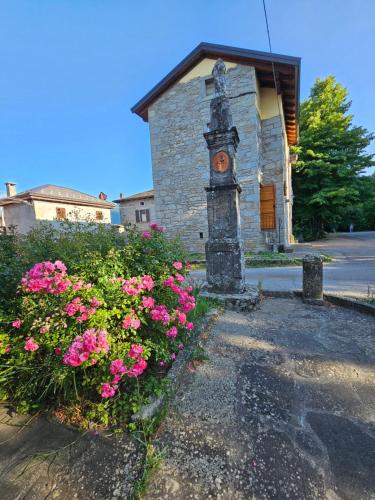 a building with a clock tower next to some flowers at La Coccola del Borgo in Fanano