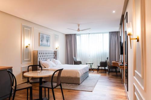 a hotel room with a bed and a table and chairs at Milestone Suites by Robinson Properties in Trivandrum