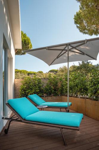 two blue chairs and an umbrella on a deck at Gallia Palace Hotel - Relais & Châteaux in Punta Ala