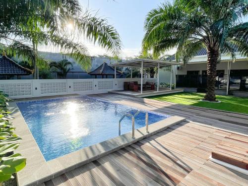 a swimming pool in front of a house with palm trees at RedDoorz Syariah Plus near Banyuwangi Airport in Dadapan