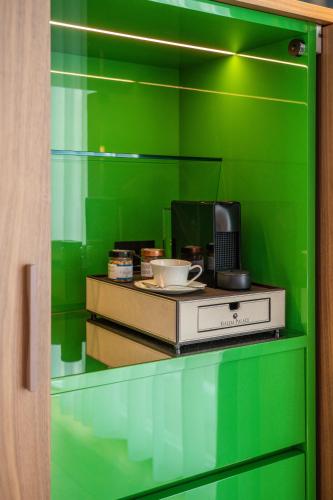 a green wall with a desk with a computer on it at Gallia Palace Hotel - Relais & Châteaux in Punta Ala