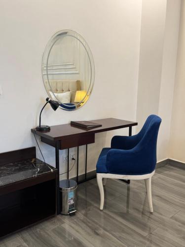 a desk with a blue chair and a mirror at The Belmorris in Multan
