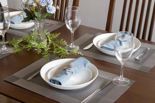 a table with plates and glasses on a wooden table at Macchiato SHONAN-Vacation Stay- in Hiratsuka