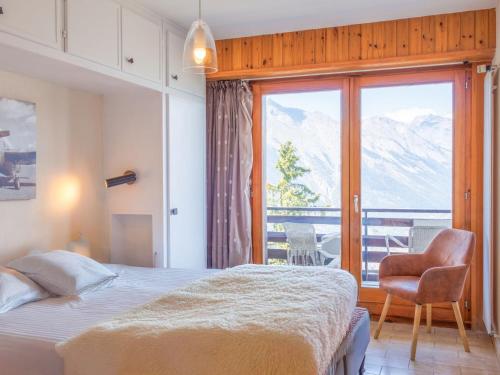 ein Schlafzimmer mit einem Bett und einem Stuhl und einem Fenster in der Unterkunft Apartment Rossignol C4 by Interhome in Nendaz