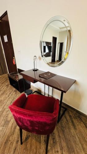 a desk with a red chair and a mirror at The Belmorris in Multan