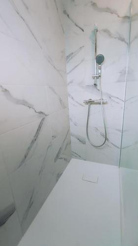 a bathroom with a shower with white marble walls at L'embellie in Mouzon