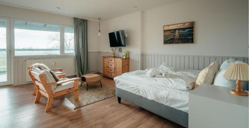 a bedroom with a bed and a chair and a television at Strandkoje - Landhaus in Neustadt in Holstein