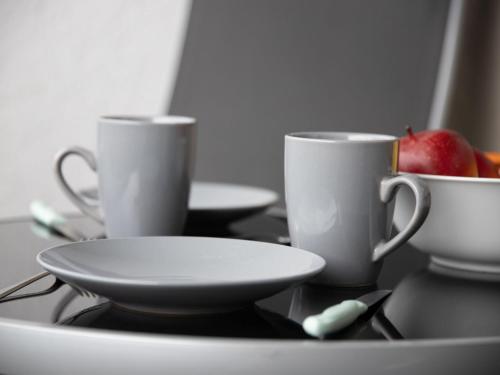 two coffee cups and a bowl of fruit on a table at Apartment La Siala Apt-37 by Interhome in Falera