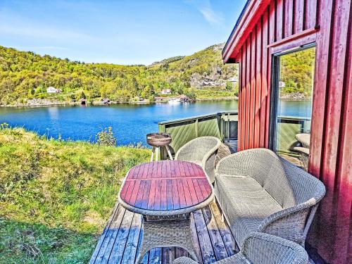 a table and chairs on a deck with a view of a lake at Holiday Home Odden - Holmen by Interhome in Lyngdal