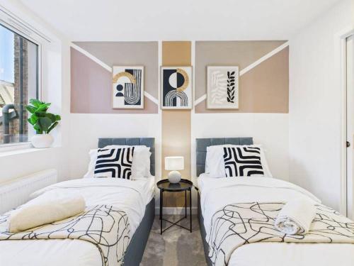two beds in a room with white walls at Stylish 2 Bedroom Flat | Sleeps 4 | in Brent Station
