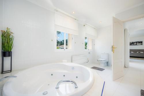 a white bathroom with a tub and a toilet at Villa Pedro strandnah ruhig zentral in Can Pastilla