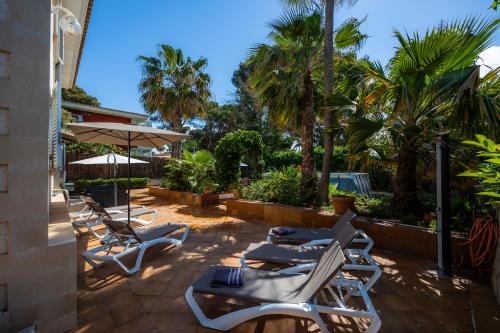 a patio with lounge chairs and palm trees at Villa Pedro strandnah ruhig zentral in Can Pastilla