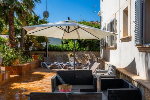 a patio with a white umbrella and chairs at Villa Pedro strandnah ruhig zentral in Can Pastilla