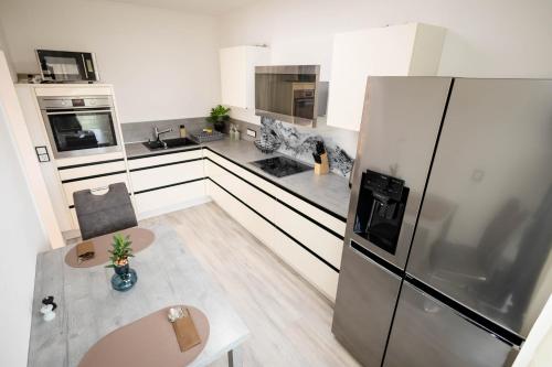 a white kitchen with a refrigerator and a table at Suites Aix la Chapelle, Exclusive Apartments, Wellness and more, Aachen Eilendorf in Aachen
