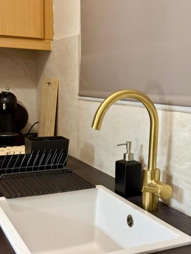 a kitchen sink with a gold faucet on a counter at Komi beach Maisonette in Kómi
