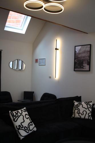 a living room with a black couch and a clock on the wall at Diesters huisje in Diest