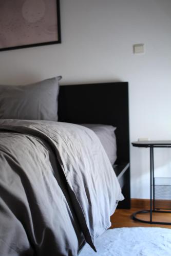 a bed with gray sheets and a table in a room at Diesters huisje in Diest
