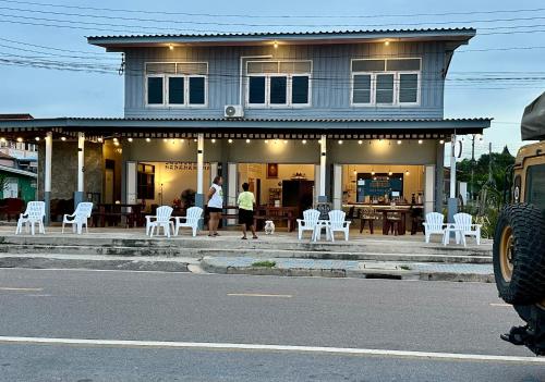 a house with white chairs and people standing in front of it at Hostel 126 Cafe' & Bar in Prachuap Khiri Khan