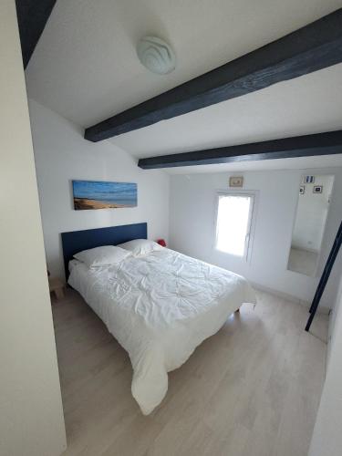 une chambre avec un grand lit blanc avec une tête de lit bleue dans l'établissement Maison de la Sau, à La Nouette