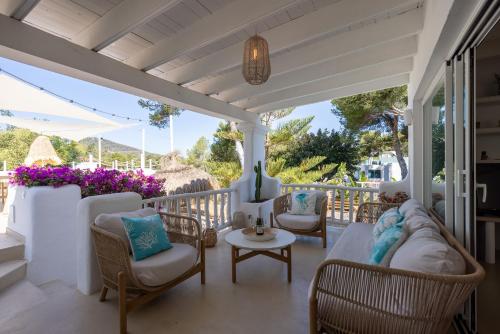a porch with chairs and a table and flowers at Villa Clara Ibiza in Santa Eularia des Riu