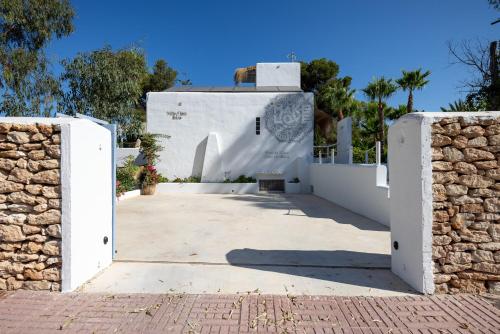 a gate to a white building with trees in the background at Villa Clara Ibiza in Santa Eularia des Riu
