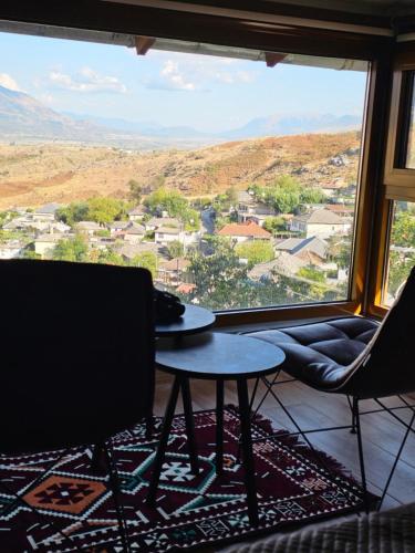 Una habitación con una mesa y sillas y una ventana grande. en Lemon Garden, en Gjirokastra
