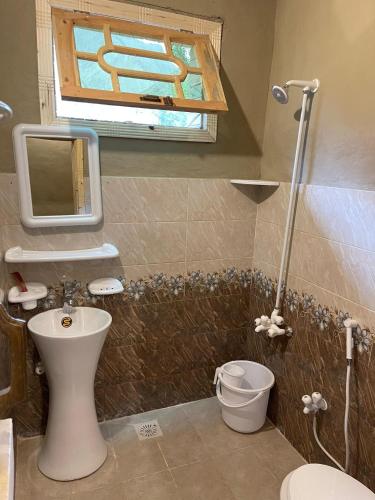 a bathroom with a toilet and a sink and a window at ANCIENT STAY by MANOKUR- E- BASA in Minapin
