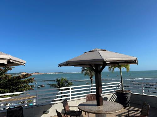 uma mesa com um guarda-sol numa varanda com vista para a praia em Pipa's Bay Apartamento - Sea View em Pipa