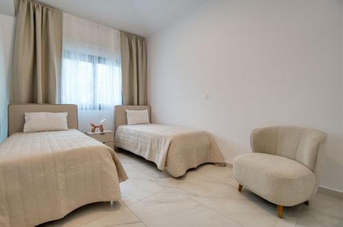 a bedroom with two beds and a chair and a window at Magnus Villa in Tala