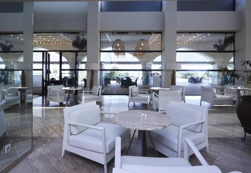 a dining room with white chairs and a table and tables at Crowne Plaza Vilamoura - Algarve by IHG in Vilamoura