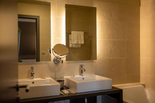 une salle de bain avec deux lavabos, un miroir et une baignoire dans l'établissement Hotel Du Lac, à Guebwiller