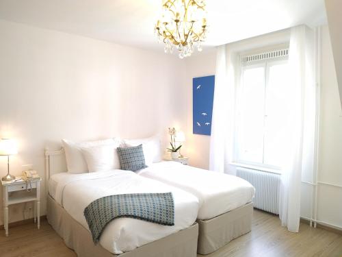 a white bedroom with a large bed and a chandelier at Hotel Eden Palace au Lac in Montreux