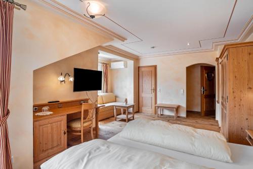 a hotel room with a bed and a desk and a television at Wein- und Klimahotel Bergfriedel in Bühlertal