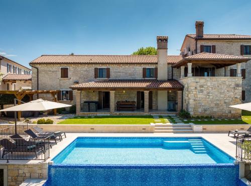 a villa with a swimming pool in front of a house at Casa Serena in Bašići
