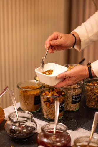 eine Person, die Essen aus einer Schüssel auf einem Tisch isst in der Unterkunft Hotel Du Lac in Guebwiller