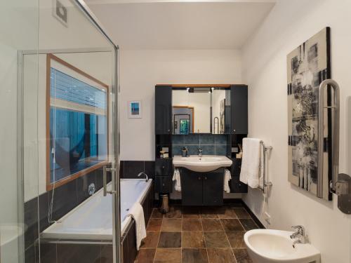 a bathroom with a tub and a sink and a bath tub at Omaha Beach House - Omaha Holiday Home in Warkworth