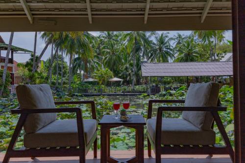 two chairs and a table with two glasses of wine at Villa Oasis in Luang Prabang