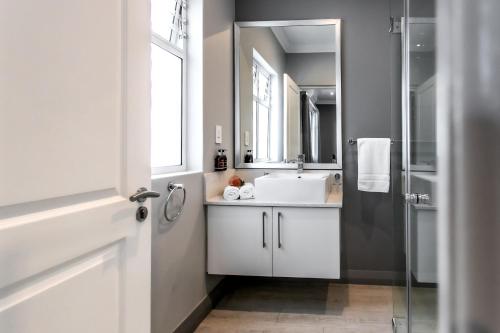 a bathroom with a white sink and a mirror at Whale Coast Ocean Villa in Hermanus