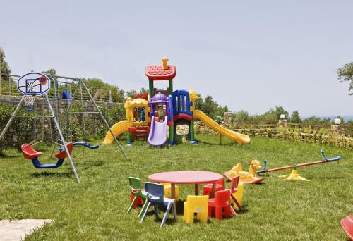 a playground with different types of play equipment in the grass at Carme Villas in Adelianos Kampos