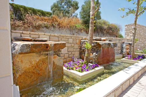a water fountain in a garden with purple flowers at Carme Villas in Adelianos Kampos