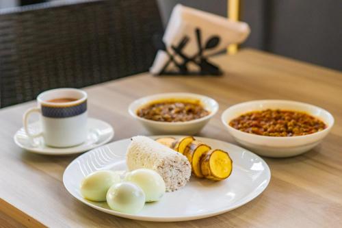 a table with a plate of food and a cup of coffee at TREE 9 Lounge -Cochin Airport in Nedumbassery