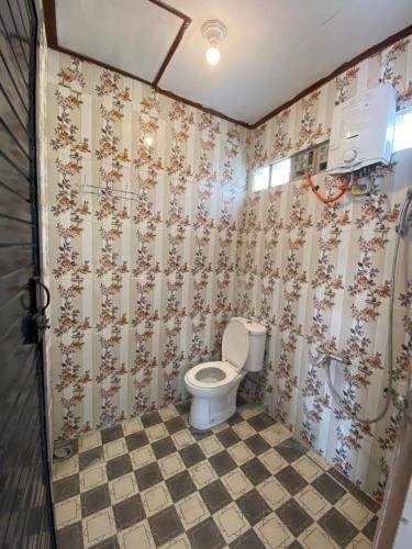 a bathroom with a toilet and a checkered floor at WISMA SUNRISE GUEST HOUSE 10 minutes by walking to the big fruit market in Berastagi in Berastagi