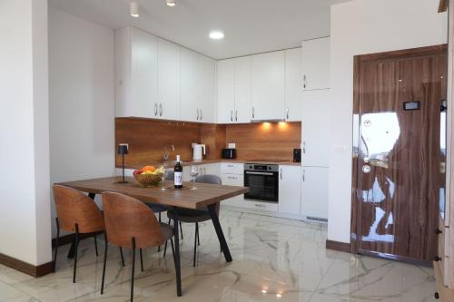 a kitchen with white cabinets and a wooden table and chairs at Belvedere at Emerald Residence Bar in Bar
