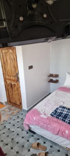 - une chambre avec un lit et une porte en bois dans l'établissement Room Taghazout, à Taghazout