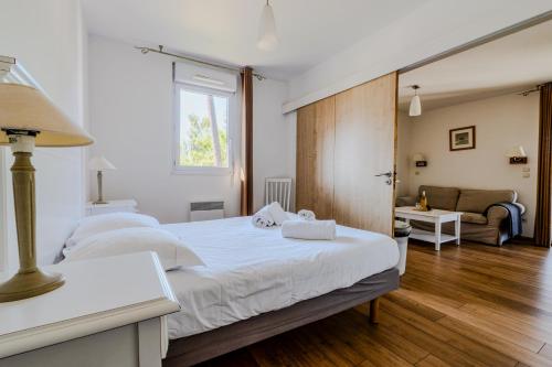 una camera con 2 letti bianchi e un divano di Appartement de type 2 cabine pour 4 personnes a Parentis-en-Born