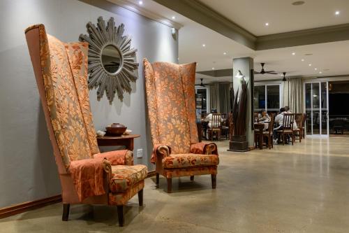 a room with two chairs and a mirror on the wall at Umthunzi Hotel and Conference in Umtentweni