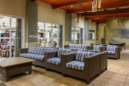 a lobby with wicker couches and tables and windows at Umthunzi Hotel and Conference in Umtentweni
