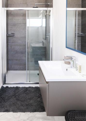 a bathroom with a shower with a sink and a mirror at Villa Ixoria Unit 1 with Private Pool by ArcoCollection in St. Julianʼs